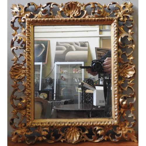 105 - AN ORNATE CARVED GILT WOOD FRAMED MIRROR, EARLY 19TH CENTURY, in the rococo style, the pierced carve... 