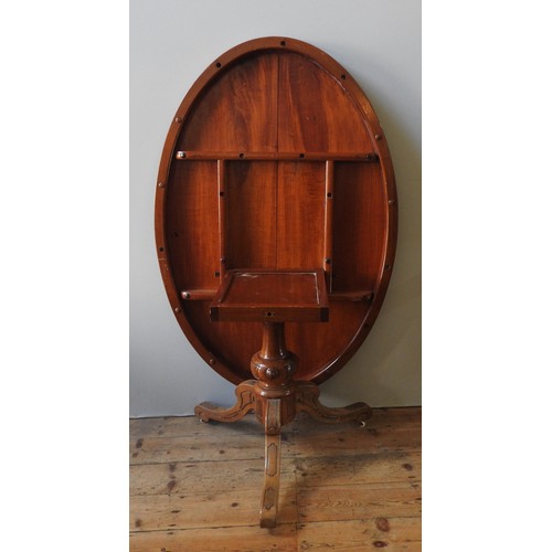 51 - A WALNUT LOO TABLE, 19TH CENTURY, the tilting oval top raised on a baluster turned pedestal raised o... 