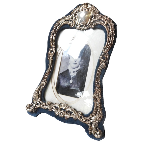 418 - A VINTAGE SILVER FRONTED PHOTOGRAPH FRAME, scroll foliate decoration with a central cartouche, suppo... 