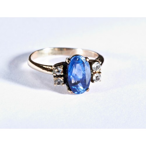 411 - A SAPPHIRE RINGthe oval mixed-cut sapphire, claw set between pairs of white stones.Ring size G... 