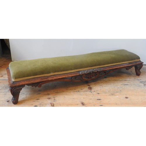 20 - A VICTORIAN MAHOGANY LONG FOOT STOOL, the overstuffed panel raised on a scroll foliate carved frame,... 