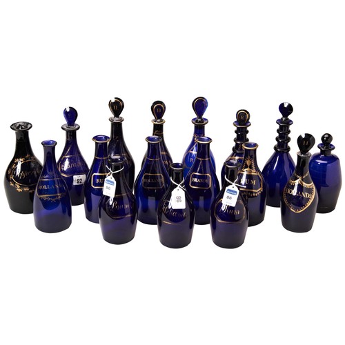 1228 - A COLLECTION OF SEVENTEEN BRISTOL-BLUE DECANTERS18TH / 19TH CENTURYmost with gilt faux spirit label ... 