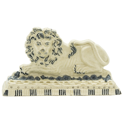 1030 - A STAFFORDSHIRE FIGURE OF A RECUMBANT LIONCirca 1830, 18cms wide