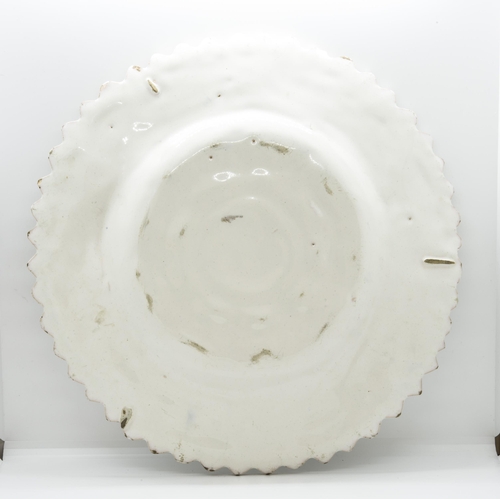 1194 - A WHITE TIN GLAZED RELIEF MOULDED CHARGER17th / 18th  century, 34.5cms wide