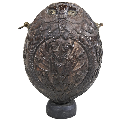 1780 - A CARVED COCONUT 'BUGBEAR' POWDER FLASK DECORATED WITH TWO OPPOSED STANDS OF ARMS14 cms long