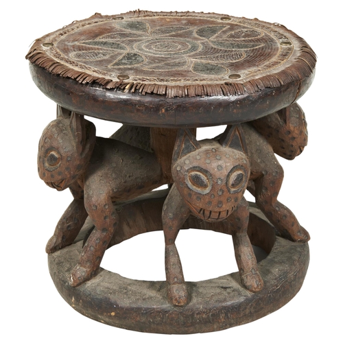 1340 - A WEST AFRICAN CARVED WOODEN TRIBAL STOOL, the woven leather and snakeskin covered top supported by ... 