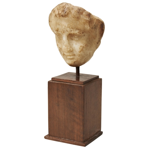 1319 - A ROMAN HEAD. Possibly a female deity but worn and fragmentary now mounted on a wooden base. 13cms h... 