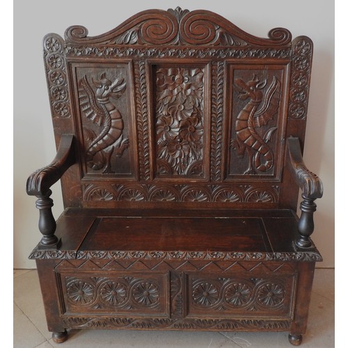 100 - A CARVED OAK SETTLE, LATE 19TH CENTURY, scrolling arch top above a panelled back with a central flor... 