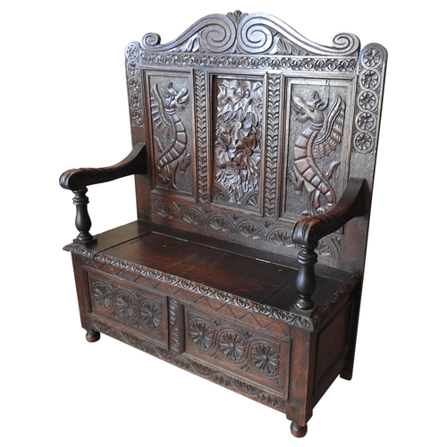 100 - A CARVED OAK SETTLE, LATE 19TH CENTURY, scrolling arch top above a panelled back with a central flor... 