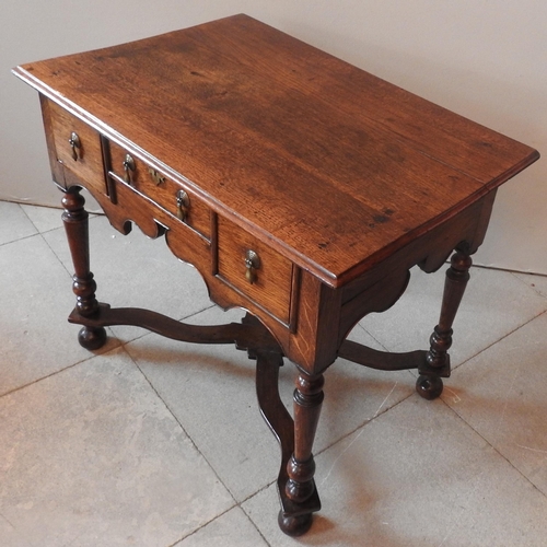 88 - AN OAK 18TH CENTURY LOW BOY, rectangular top over three frieze drawers with a shaped apron, raised o... 