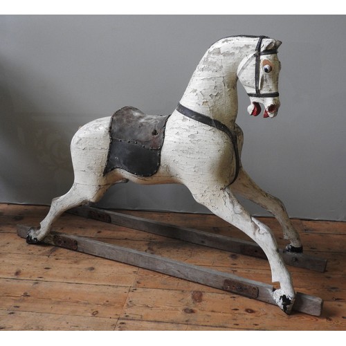 501 - A LARGE VINTAGE CARVED WOODEN ROCKING HORSE, cream painted with a leather saddle, missing the trestl... 