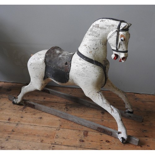 501 - A LARGE VINTAGE CARVED WOODEN ROCKING HORSE, cream painted with a leather saddle, missing the trestl... 