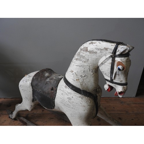 501 - A LARGE VINTAGE CARVED WOODEN ROCKING HORSE, cream painted with a leather saddle, missing the trestl... 