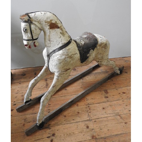 501 - A LARGE VINTAGE CARVED WOODEN ROCKING HORSE, cream painted with a leather saddle, missing the trestl... 