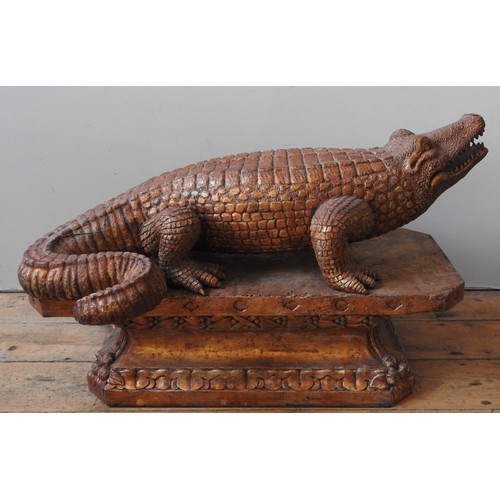 502 - A LARGE CARVED WOODEN DECORATIVE MODEL OF AN ALLIGATOR, standing foursquare on a foliate carved octa... 