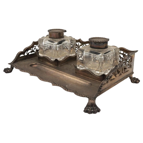 553 - A SILVER INKSTAND THE RETICULATED UPSTAND AROUND TWO SILVER-TOPPED GLASS INKWELLS and upon paw feet ... 