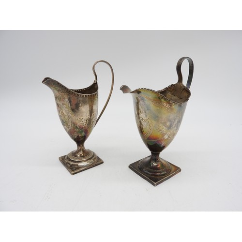 523 - TWO GEORGIAN HELMET FORM CREAM JUGS, both raised on square feet, both monogrammed and engraved with ... 