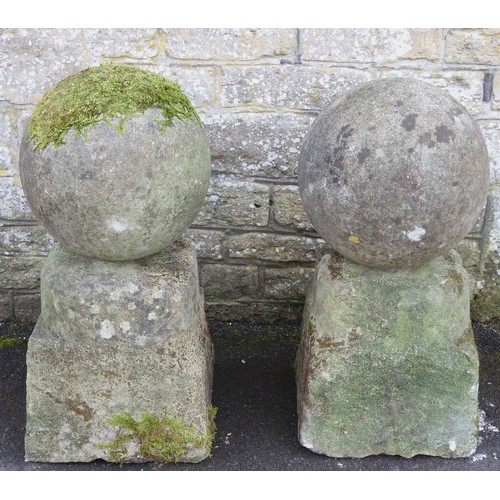 690 - A PAIR OF ARCHITECTURAL STONE BALLS ON TAPERING STONE PLINTHS, PROBABLY 19TH CENTURY.67 cms high, 29... 