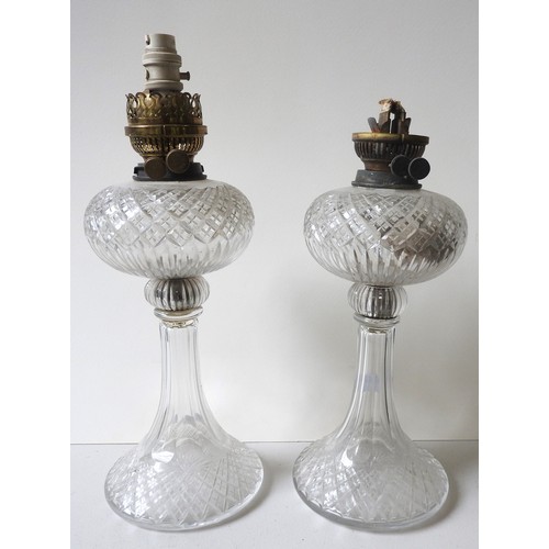 63 - A PAIR OF CUT GLASS OIL LAMPS, early 20th century, with flared bases, the wick holders later changed... 