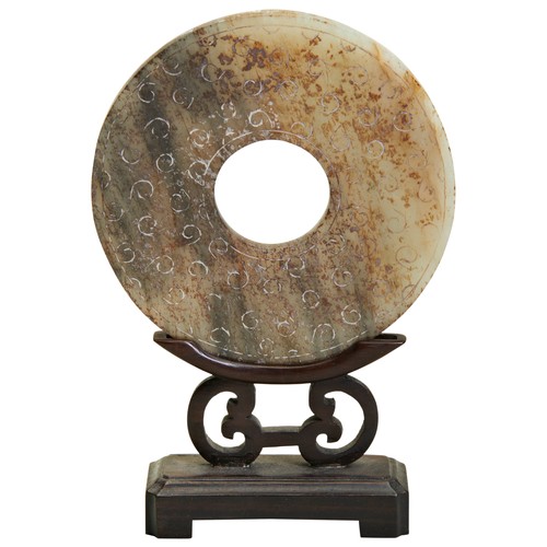 284 - A JADE BI DISC ON A WOODEN STAND 20TH CENTURY jade bi disc carved with spiral bosses on the surface.... 