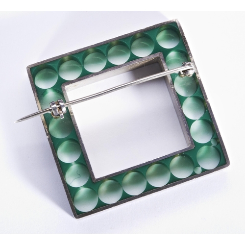 316 - NUALA JAMISON; AN ACRYLIC AND SILVER BROOCHThe square brooch of clear acrylic with green circles.Bro... 