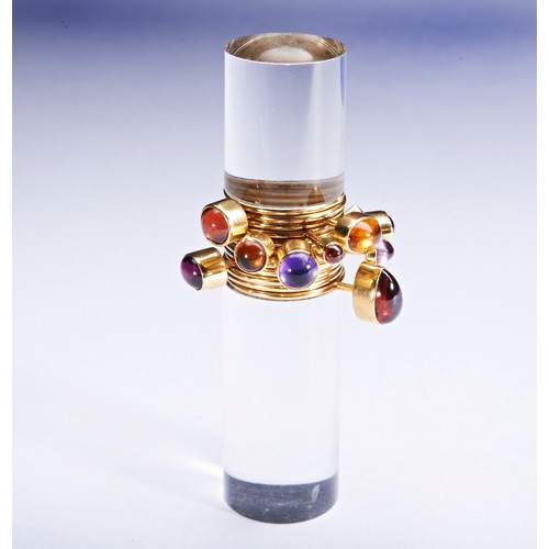 319 - WENDY RAMSHAW; AN AMETHYST, GARNET, AND GOLD RING ON AN ACRYLIC STANDthe ring composed of twelve ban... 