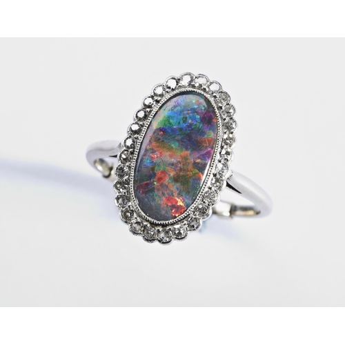 339 - AN EDWARDIAN BLACK OPAL AND DIAMOND RINGthe oval-cut opal millegrain collet set within a border of t... 