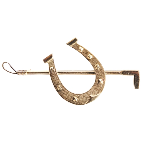 331 - AN 18 CARAT GOLD BROOCHdesigned as a horseshoe and riding crop, the horseshoe with textured surface.... 