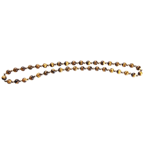 303 - A TIGER'S EYE NECKLACEthe uniform row of tiger's eye beads spaced by gilt beads. Total weight 126gms... 