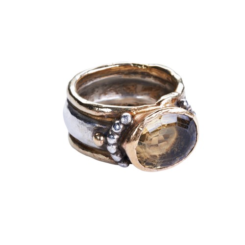 314 - CITRINE, SILVER AND GOLD RINGthe oval mixed-cut citrine collet set in a heavy silver and gold band w... 