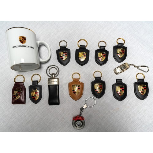 357 - A NUMBER OF ORGIINAL PORSCHE KEYRINGS, AND BRANDED MUG