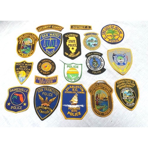 70 - OVER 50 US AND GERMAN POLICE BADGES Over 50 sew-on and cast metal badges covering many US cities, co... 