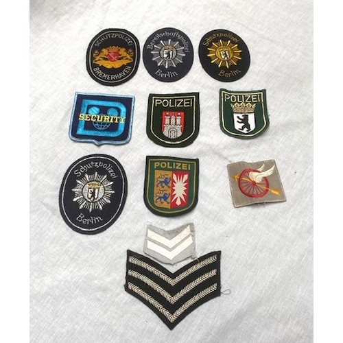 70 - OVER 50 US AND GERMAN POLICE BADGES Over 50 sew-on and cast metal badges covering many US cities, co... 