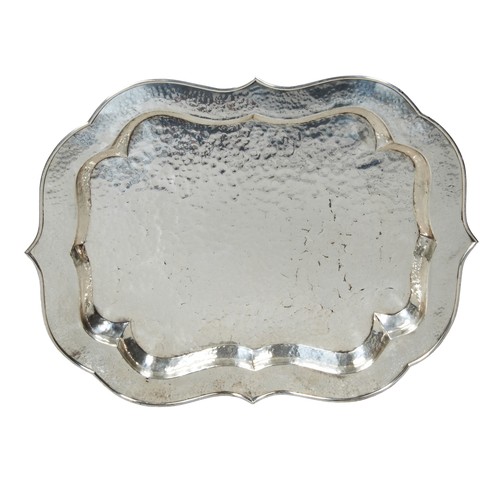 778 - A CHROMED SCROLL EDGE TRAY, 20TH CENTURY, escutcheon shape with planished finish, raised on a foldin... 