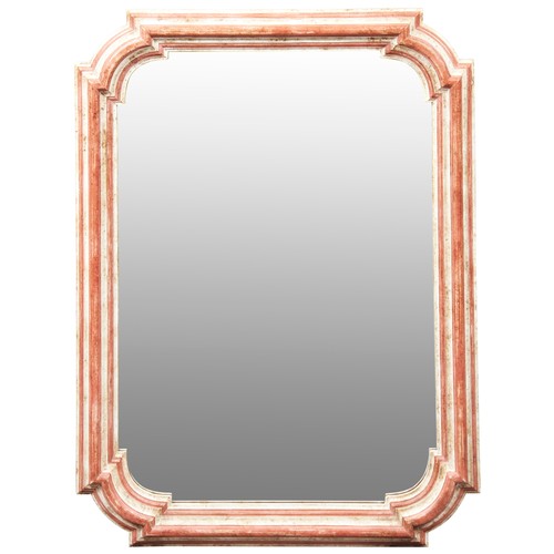 635 - A CONTEMPORARY DECORATIVE WALL MIRROR mounted in a canted corner frame painted salmon pink on a crea... 