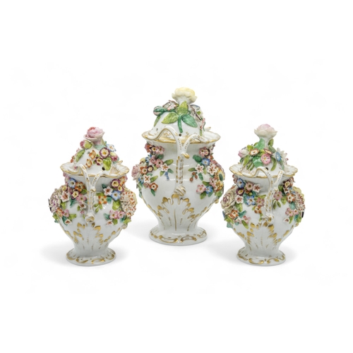 297 - A FLORAL ENCRUSTED GARNITURECirca 1840s, 22cms high