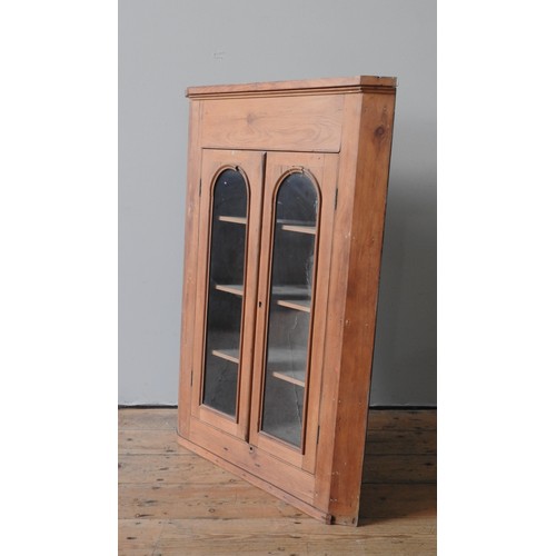 39 - A WAXED PINE CORNER CABINET, the arch glazed doors opening to reveal three interior shelves111 x 55 ... 