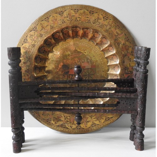 144 - AN INDIAN BRASS TRAY TABLE,  central lobed recess with chased figural decoration, raised on a foldin... 