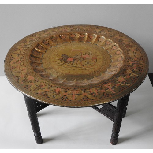 144 - AN INDIAN BRASS TRAY TABLE,  central lobed recess with chased figural decoration, raised on a foldin... 