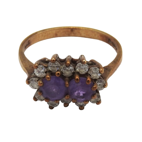 458 - A 9CT GOLD AMETHYST SET DRESS RING, the two amethyst stones enclosed by twelve C.Z stones, the shank... 