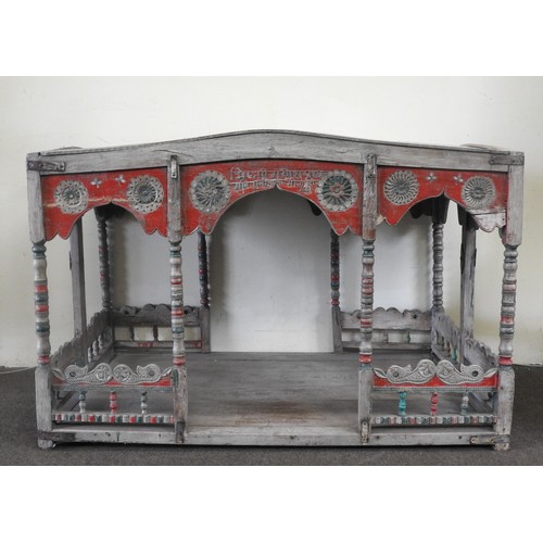 115 - AN INDIAN CARVED TEAK PALANQUIN, the domed zinc canopy raised on bobbin turned supports with polychr... 