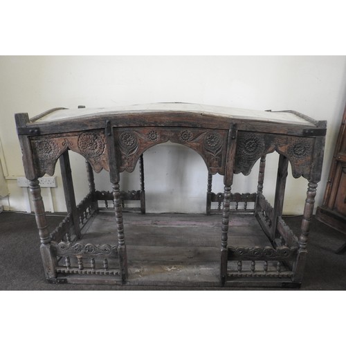 105 - A CARVED INDIAN HARDWOOD PALANQUIN, the canopy raised on bobbin turned supports, above a galleried p... 
