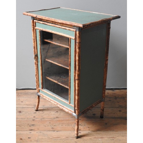 32 - A GREEN PAINTED BAMBOO CABINET, the glazed panel door opening to reveal three interior shelves