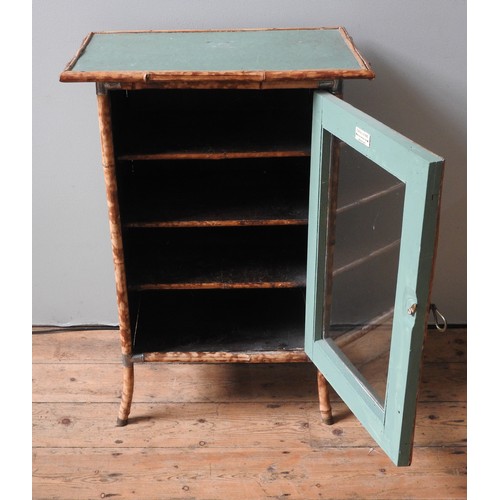 32 - A GREEN PAINTED BAMBOO CABINET, the glazed panel door opening to reveal three interior shelves