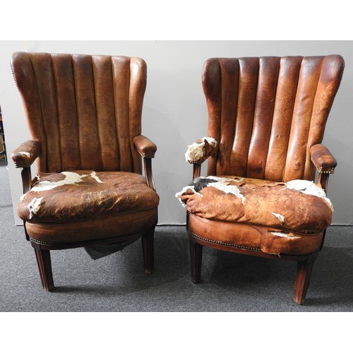 42 - A PAIR OF VINTAGE TAN LEATHER ARMCHAIRS, elegant shell backs over a wide seat panel, flanked by open... 