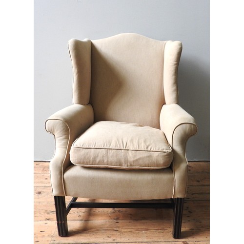 41 - A GEORGE III CAMEL BACK WING ARMCHAIR, with scrolling arms, covered in a beige fabric raised on squa... 