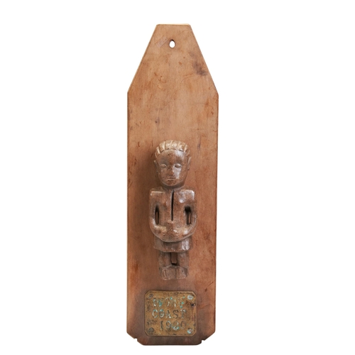 155 - A CARVED WOODEN IVORY COAST FIGURE, it’s hands clasped holding a vessel, mounted on a Back board and... 