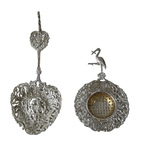 441A - AN ORNATE DUTCH SILVER SUGAR SPOON AND TEA STRAINER, both with ornate pierced chased decoration, the... 