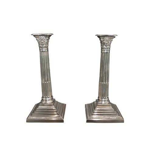 795 - A PAIR OF SILVER CORINTHIAN FORM CANDLESTICKS, raised on graduated square weighted basesmarked Barke... 