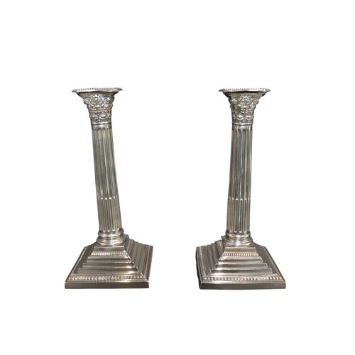 795 - A PAIR OF SILVER CORINTHIAN FORM CANDLESTICKS, raised on graduated square weighted basesmarked Barke... 